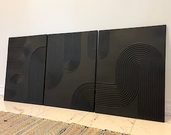 May include: Three black wall panels with a raised geometric design. The panels are made of wood and have a dark, almost black finish. The design is made up of circles and curved lines.