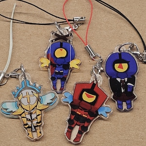 May include: A collection of acrylic charms featuring cartoon characters with various designs. The charms have attached lanyards and keychains. The characters are in various colors, including blue, red, yellow, and white.