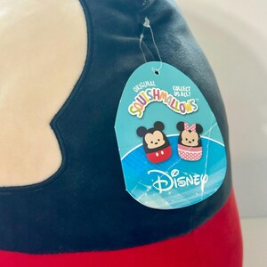 Op de afbeelding: Een groot, pluche Mickey Mouse Squishmallow-speelgoed. Het speelgoed is voornamelijk zwart, rood en wit, met een label met Mickey en Minnie Mouse-illustraties en het Disney-logo. Op het label staat "Original Squishmallows" en "Collect Us All!"