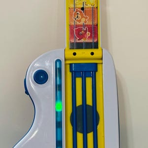 Pode incluir: Uma guitarra de brinquedo Baby Einstein colorida. &Eacute; principalmente branca e amarela, com detalhes azuis. Apresenta gr&aacute;ficos de animais e um bot&atilde;o vermelho. O logotipo da Baby Einstein &eacute; vis&iacute;vel.