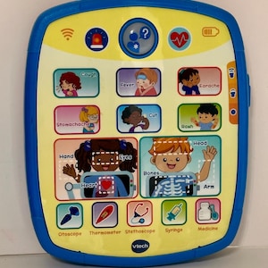 May include: A blue and yellow VTech electronic learning toy with a screen displaying medical icons, illustrations of children with health symptoms, and labeled body parts including hand, eyes, heart, head, bones, and arm, plus medical tools.