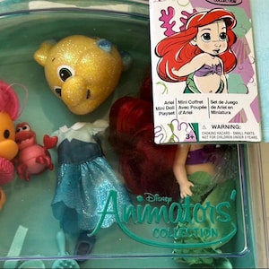 May include: Ariel Mini Doll Playset from the Disney Animators' Collection. The set includes a doll with red hair, a blue dress, and several character figures. The packaging features Ariel's image and the text "Ariel Mini Doll Playset".