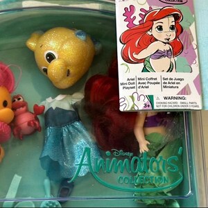 May include: Ariel Mini Doll Playset from the Disney Animators' Collection. The set includes a doll with red hair, a blue dress, and several character figures. The packaging features the Ariel character and the text "Ariel Mini Coffret Mini Doll Playset".