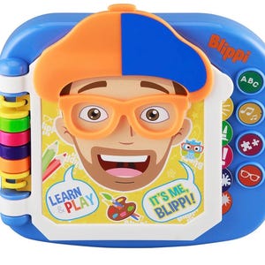 May include: A blue and white Blippi learning toy with a colorful design. The toy features a cartoon face with orange glasses and a hat. The text "Learn & Play" and "It's Me, Blippi!" are visible. Buttons with ABC, music notes, and other icons are on the side.