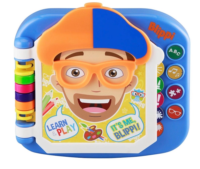 May include: A blue and white Blippi learning toy with a colorful design. The toy features a cartoon face with orange glasses and a hat. The text "Learn & Play" and "It's Me, Blippi!" are visible. Buttons with ABC, music notes, and other icons are on the side.