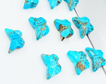 May include: Ten turquoise butterfly shaped cabochons with brown and gold marbling. The cabochons are carved with a geometric pattern.