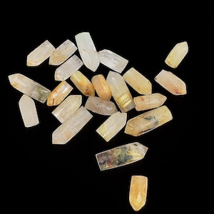 May include: A white ceramic mug with a black handle and the text "But First, Coffee" in a bold, black font. The mug is set against a blurred background, suggesting a cozy setting.