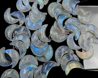 May include: A collection of 30 crescent moon shaped rainbow moonstone cabochons. The stones are a milky white color with iridescent blue and green flashes.