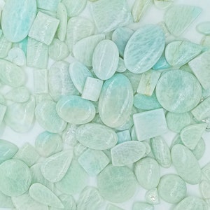May include: A collection of light green, translucent, oval and rectangular shaped gemstones. The stones have a smooth, polished finish.