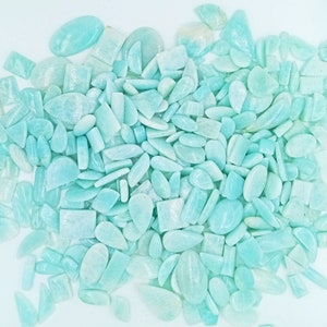 K&ouml;nnte beinhalten: Eine gro&szlig;e Sammlung von hellblauen und gr&uuml;nen Edelstein-Cabochons in verschiedenen Formen und Gr&ouml;&szlig;en. Die Cabochons sind in einem zuf&auml;lligen Muster angeordnet und bereit f&uuml;r die Verwendung in der Schmuckherstellung.