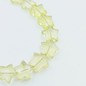 May include: A strand of light yellow star-shaped beads. The beads are made of glass and have a translucent appearance.