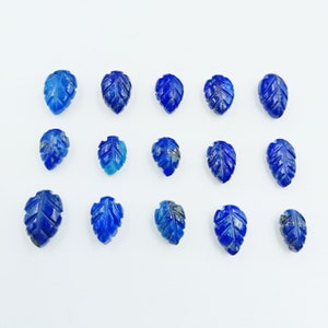 Könnte beinhalten: Eine Sammlung von 15 blauen Lapislazuli-Cabochons in Blattform. Die Cabochons sind in Blattform geschnitten und haben eine glatte, polierte Oberfläche.