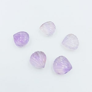 May include: Five carved amethyst gemstone beads in the shape of a heart. The beads are a light purple color and have a smooth, polished finish.