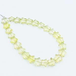 May include: A strand of light yellow star-shaped beads. The beads are faceted and translucent.