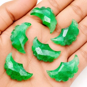 May include: Five small, crescent-shaped gemstones with a vibrant green color and a faceted surface. Each piece features a curved design with a scalloped outer edge, reflecting light across the polished, angular surfaces of the green stones.