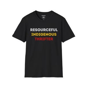 Könnte beinhalten: Schwarzes T-Shirt mit dem Aufdruck "RESOURCEFUL INDIGENOUS THRIFTER" in Weiß, Gelb und Rot. Das Shirt hat einen Rundhalsausschnitt und scheint aus Baumwolle zu sein.