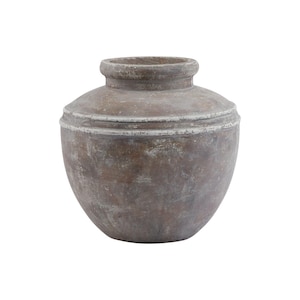 May include: A round, wide-bodied vase with a short, thick neck and a prominent horizontal ridge around the upper section. The surface features a weathered, matte brown finish with subtle white, chalky highlights and a textured, earthy appearance.