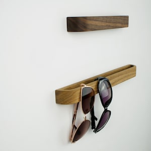 Minimalist wooden eyewear holder crafted from American walnut, self adhesive wall hook for reading glasses, functional and stylish organizer for contemporary interiors