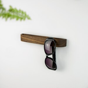 Minimalist wall hook for reading glasses, handcrafted from solid walnut wood, self adhesive installation without drilling, practical wooden glasses organizer for modern interiors