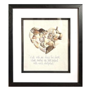May include: Framed artwork with a heart made of seashells in white, beige, and brown. The artwork includes the quote: "Walk with me along the shore, where worries are left behind with each footprint."