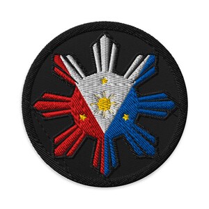 Op de afbeelding: Geborduurde ronde patch met het zon- en drie sterrenontwerp van de Filipijnse vlag. De patch heeft een zwarte rand en het centrale ontwerp bevat rode, witte en blauwe segmenten met gele sterren en een zon.
