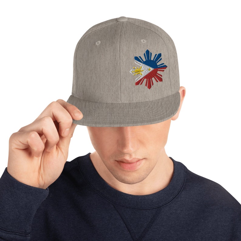 Pu&ograve; includere: Un berretto da baseball grigio a misura con un design ricamato della bandiera filippina a forma di sole.
