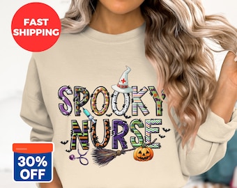 May include: Beige sweatshirt with the words "SPOOKY NURSE" in colorful, patterned letters. The design includes a witch hat, syringe, broom, pumpkin, and bats, perfect for Halloween. A red circle with "FAST SHIPPING" is in the upper left corner.