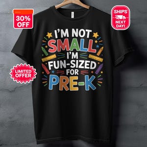May include: Black t-shirt with the text "I'M NOT SMALL I'M FUN-SIZED FOR PRE-K" in colourful letters. The design includes images of crayons and rulers. The shirt has a 30% off sticker and a "Limited Offer" sticker.