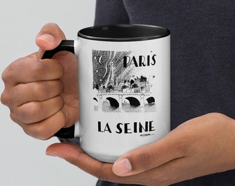 May include: White ceramic mug with a black rim and handle. The mug features a black and white illustration of the Seine River in Paris, France. The text "Paris" and "La Seine" are printed on the mug.