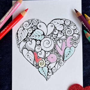Herz Postkarte, die mit Buntstiften bemalt werden kann. Buntstifte liegen neben der Postkarte und Herzen liegen zur Deko um die Postkarte