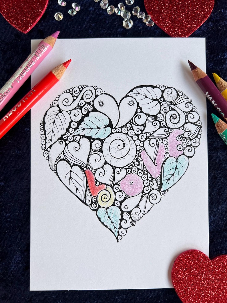 Herz Postkarte, die mit Buntstiften bemalt werden kann. Buntstifte liegen neben der Postkarte und Herzen liegen zur Deko um die Postkarte