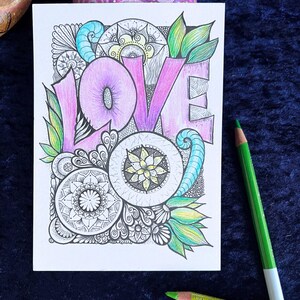 Love Postkarte auf einer blauen Decke liegend mit Buntstiften drum herum