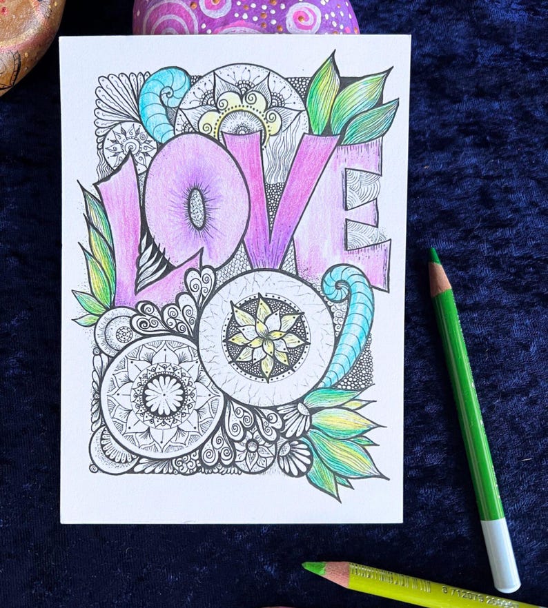 Love Postkarte auf einer blauen Decke liegend mit Buntstiften drum herum