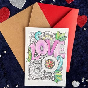 Handgezeichnete Love Postkarte zum Ausmalen (mit Buntstiften angemalt) und zwei Briefumschläge in rot und braun auf dunklem Stoff dekoriert mit Herz Deko