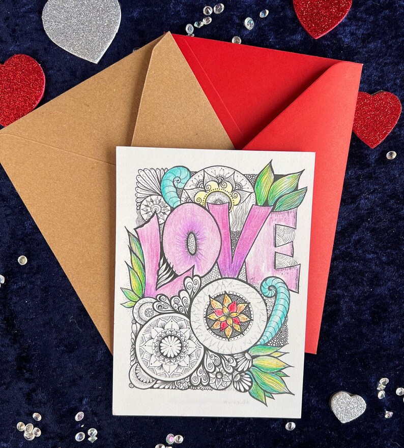 Handgezeichnete Love Postkarte zum Ausmalen (mit Buntstiften angemalt) und zwei Briefumschläge in rot und braun auf dunklem Stoff dekoriert mit Herz Deko