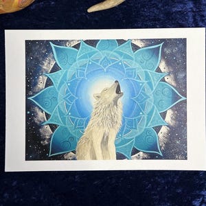 Wolf Krafttier Bild "Der Ruf". Gicleé Druck. Zu sehen ist ein weißer Wolf, der ruft, umgeben von einem Mandala in blau-Tönen. Das Original Bild wurde gemalt von der Künstlerin Miriam Linda Weiss.