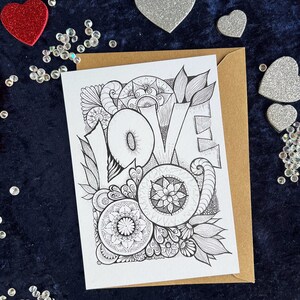 Love Postkarte mit Mandala und Zentangle Muster, im Hintergrund liegt ein brauner Umschlag und Herz Deko