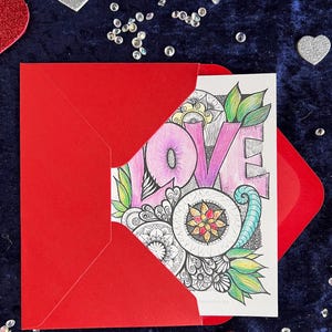 Love Postkarte selbst gemalt mit zentangle und Mandala Muster ausgemalt in einem roten Umschlag. Zur Deko liegen Herzen drumherum