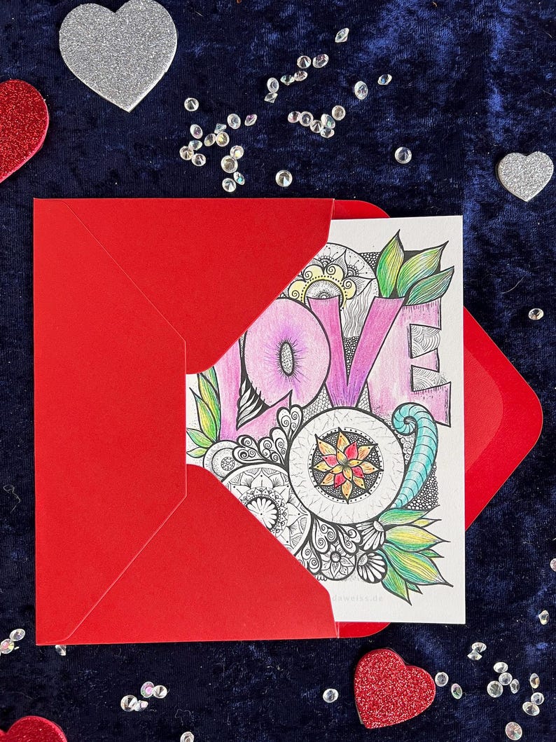 Love Postkarte selbst gemalt mit zentangle und Mandala Muster ausgemalt in einem roten Umschlag. Zur Deko liegen Herzen drumherum