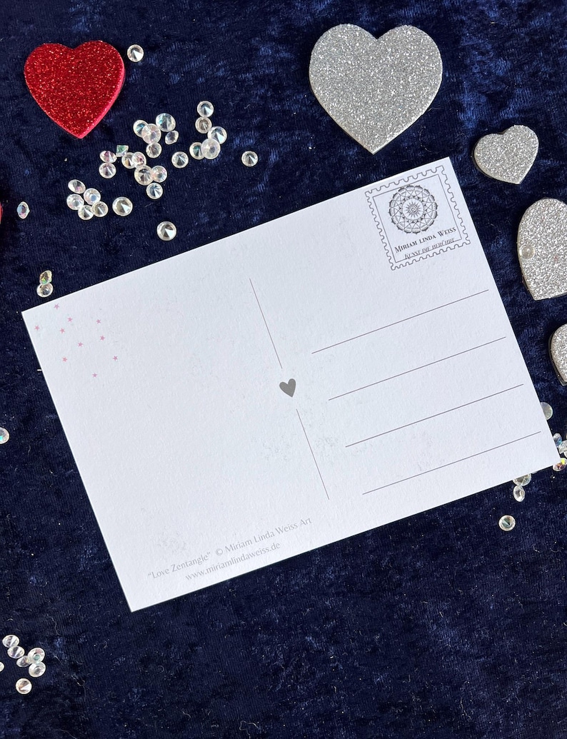 Rückseite der love Postkarte auf einer blauen Decke liegend mit Herz Deko drumherum