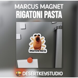 May include: A refrigerator magnet featuring a cartoon rigatoni pasta character with an open mouth. The magnet is on a gray refrigerator door, with the text "MARCUS MAGNET RIGATONI PASTA" at the top. The magnet is from Desert Key Studio.