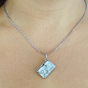 May include: A silver chain necklace with a silver charm pendant shaped like a closed envelope with a heart, a star, and a circle on the front. The envelope has the word "LOVE" printed on it.