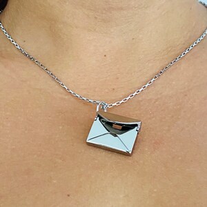 May include: A silver chain necklace with a silver envelope pendant.