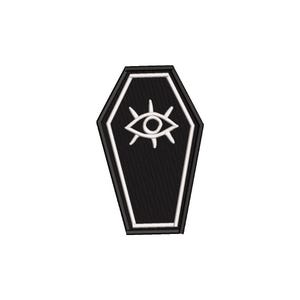 Peut inclure: Un écusson noir en forme de cercueil avec une bordure blanche et un symbole d'œil blanc. Le patch est brodé avec un aspect texturé, et le symbole de l'œil est centré sur le cercueil.