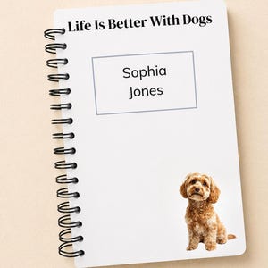 May include: A spiral-bound notebook with the text "Life Is Better With Dogs" at the top. Below, a rectangular box contains the names "Sophia Jones." A brown dog illustration is at the bottom right. The notebook is white.
