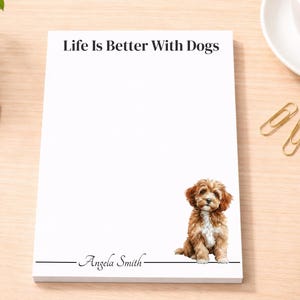 May include: A white rectangular notepad featuring the black text Life Is Better With Dogs at the top. The bottom section displays the name Angela Smith in a script font above a horizontal line, with a small illustration of a brown puppy.