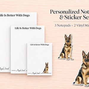 May include: A personalized notepad and sticker set featuring three white notepads of varying sizes and two vinyl German Shepherd stickers. Each notepad displays the text Life Is Better With Dogs and the name Angela Smith with a dog illustration.