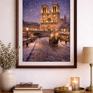 Op de afbeelding: Ingelijste prent van de Notre Dame kathedraal in Parijs tijdens een sneeuwbui. De afbeelding toont de verlichte kathedraal, een geplaveide straat en een paardenkoets. De scène is omlijst in een donkerbruine houten lijst.