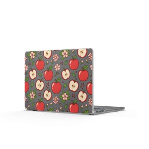Op de afbeelding: Een laptop met een grijze hoes met een patroon van rode appels, appelschijfjes, roze bloemen en groene bladeren. Het ontwerp wordt herhaald over de hoes, waardoor een samenhangende en visueel aantrekkelijke uitstraling ontstaat.