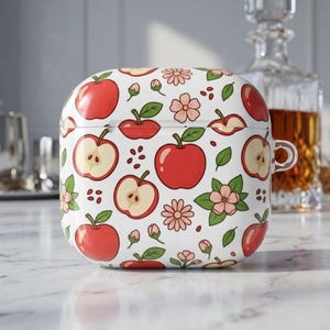 Op de afbeelding: Witte AirPods-hoes met een patroon van rode appels, appelschijfjes, roze bloemen, groene bladeren en bruine zaden. De hoes heeft een afgeronde vierkante vorm en een doorzichtige lus.